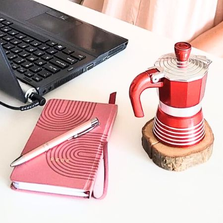 Konsultacja online Podróż Mistyczna – laptop, notes i kawa podczas spotkania z Katarzyną Gościniewicz.